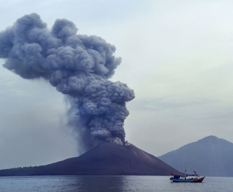 Zdjęcie przedstawia obficie dymiący wulkan na wyspie.