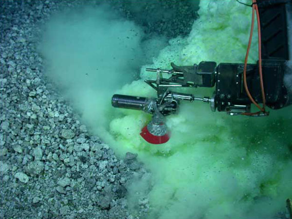 Zdjęcie przedstawia pobieranie próbek przez pojazd podwodny, widać mnóstwo bąbelków i robotyczne ramię