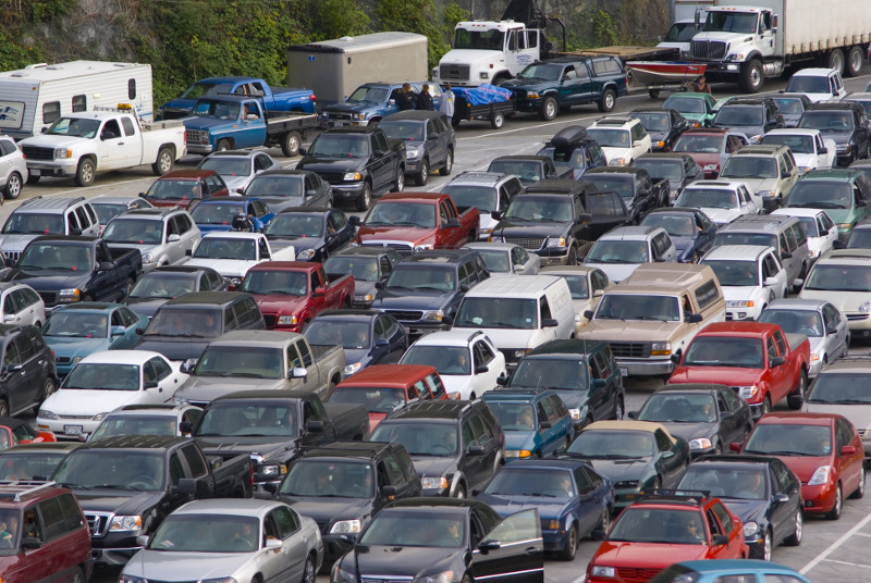 Zdjęcie przedstawia wiele rzędów samochodów stojących w korku na autostradzie.