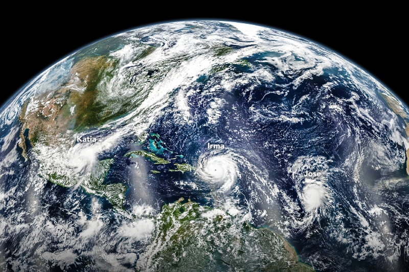 Zdjęcie satelitarne przedstawia północną półkulę, Atlanty i Amerykę Śodkową, nad którymi widoczne są trzy duże wiry - huragany.