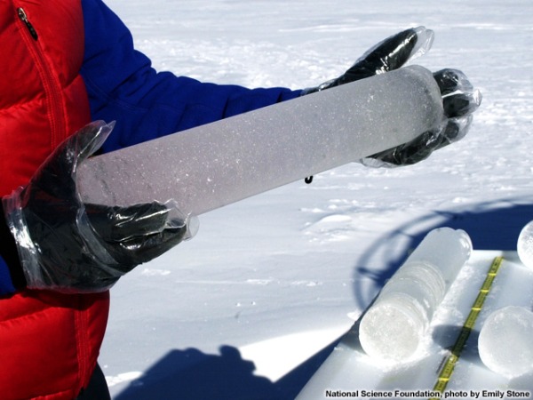 Zdjęcie przedstawia rdzen lodowy w rękach badacza