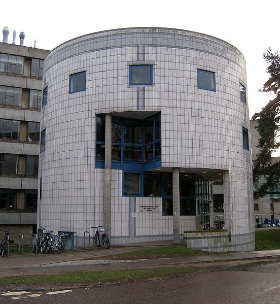 Zdjęcie przedstawia freagment budynku w kształcie cylindra z jasnyh cegieł.