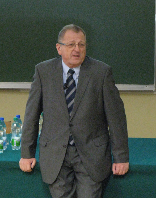 Zdjęcie: profesor Łukasz A. Turski. Zdjęcie przedstawia starszego mężczyznę opartego o biurko. 
