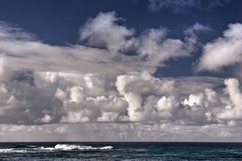 Zdjęcie przedstawia ocean nad którym unoszą się liczne, rozbudowane w pionie chmury kłębiaste.