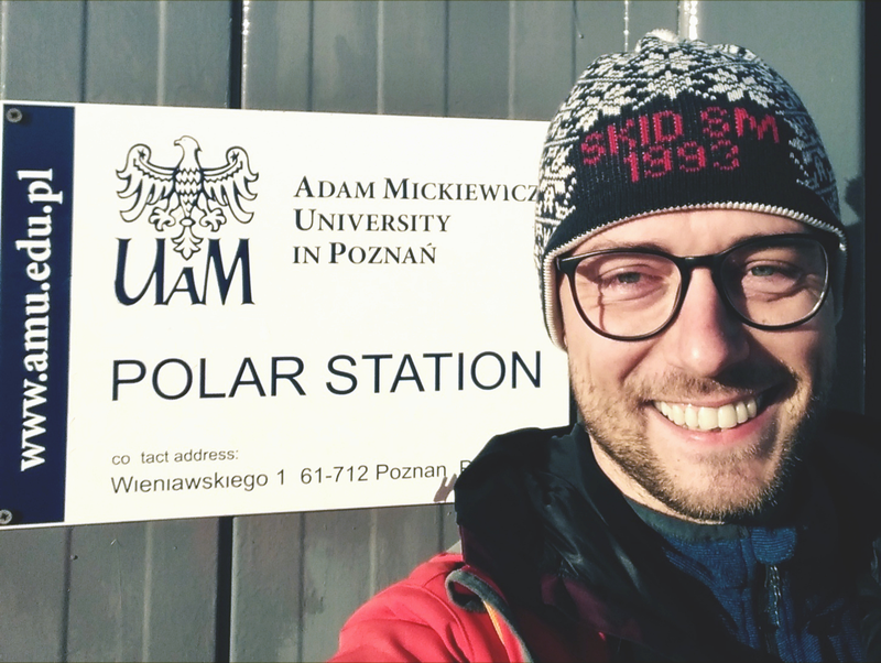 Jakub Małecki - zdjęcie z tabliczką stacji polarnej UAM.