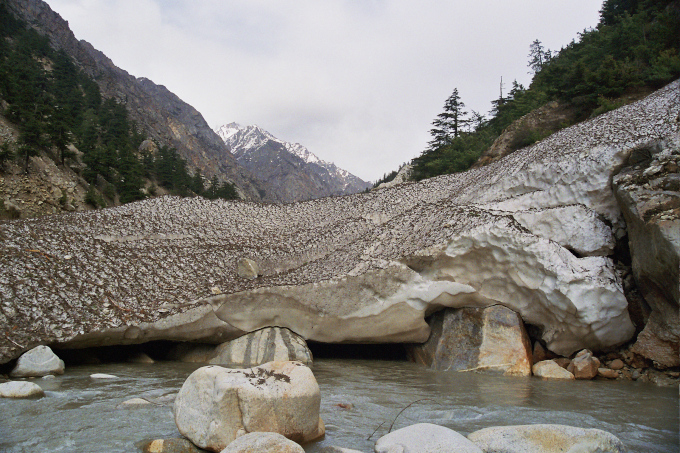 Zdjęcie: rzeka Bhagirathi wypływająca spod płata brudnego lodu, wokół górski krajobraz