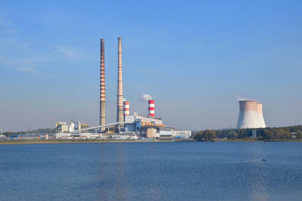 Zdjęcie: elektrownia w Rybniku, widoczny duży zakład przemysłowy z wysokimi kominami, umiejscowiony nad zbiornikiem wodnym]