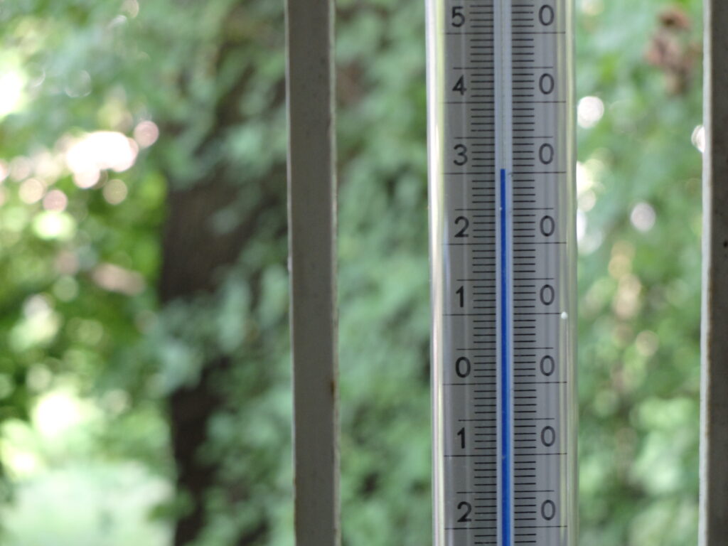 Zdjęcie termometru zaokiennego pokazującego temperaturę 31°C w cieniu.
