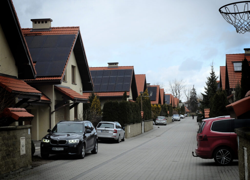 Suburbanizacja. Zdjęcie przedstawia uliczkę z szeregiem jednakowych niedużych domków. 