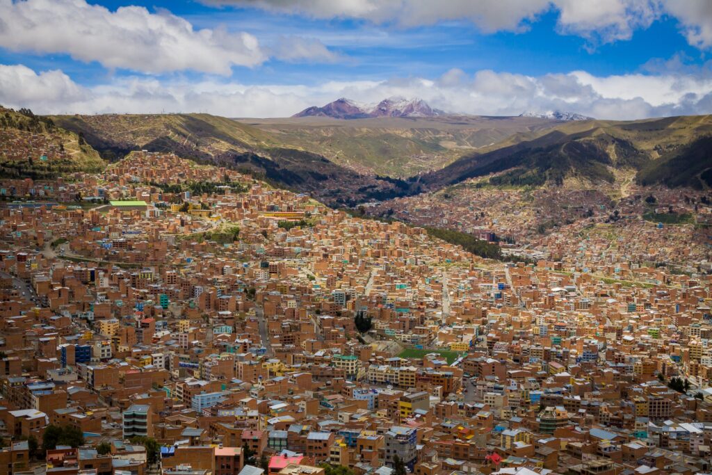 Zdjęcie przedstawia miasto La Paz. Widać na nim ogromną ilość budynków, w oddali wysokie góry pokryte lodowcami.