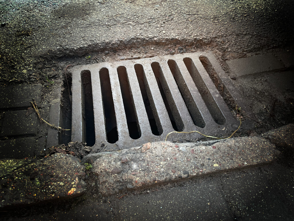 Zdjęcie: kratka kanalizacji ściekowej na ulicy. 