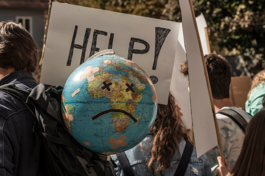 Obrazek dekoracyjny: demonstracja związana ze zmianą klimatu, uczestnik niesie globus z narysowaną smutną buzią.