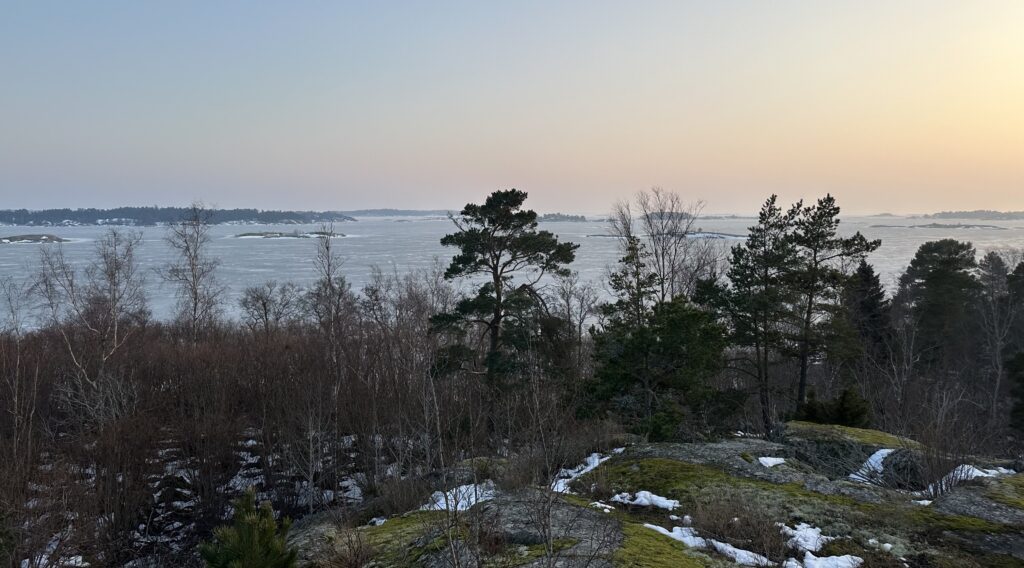 Zdjęcie: Tvärminne, okolice stacji pomiarowej. Widać skalisto-drzewiasty krajobraz z morzem i kolejnymi wyspami w tle. 