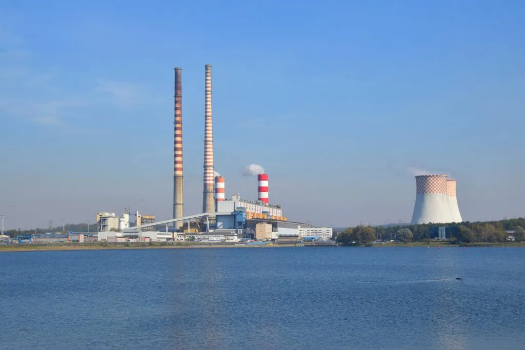 Zdjęcie: elektrownia w Rybniku, widoczny duży zakład przemysłowy z wysokimi kominami, umiejscowiony nad zbiornikiem wodnym]