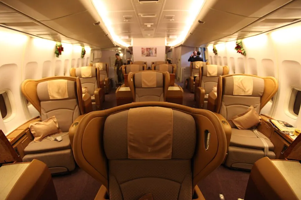 Zdjęcie: wnętrze przedziału pierwszej klasy w samolocie, duże fotele z dużymi odległościami pomiędzy nimi. 