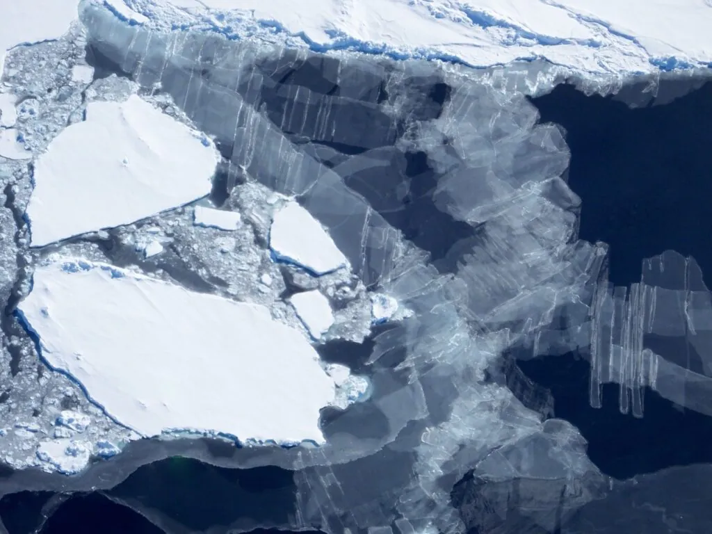 Zdjęcie lotnicze: lód morski. Widać grubsze i cieniutkie (niemal przezroczyste) tafle lodu. 