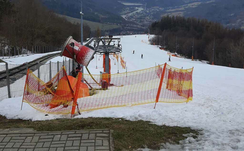 Polska zima: zdjęcie armatki śnieżnej na sztucznie naśnieżanym stoku narciarskim na górze Żar. 