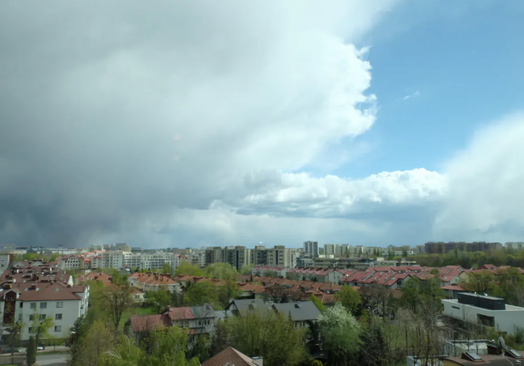 Zdjęcie: burza i deszcz w Warszawie. Widać krajobraz miejski z ciężkimi chmurami. 