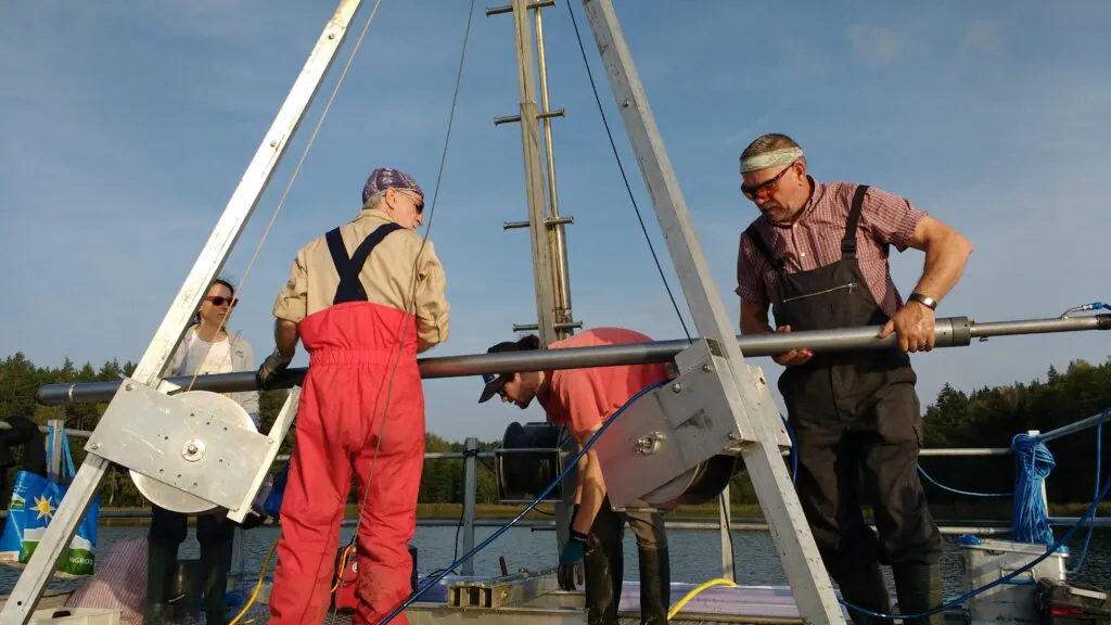 Zdjęcie: wydobycie rdzeni osadowych z dna Jeziora Żabińskiego. Paleoklimatologia.