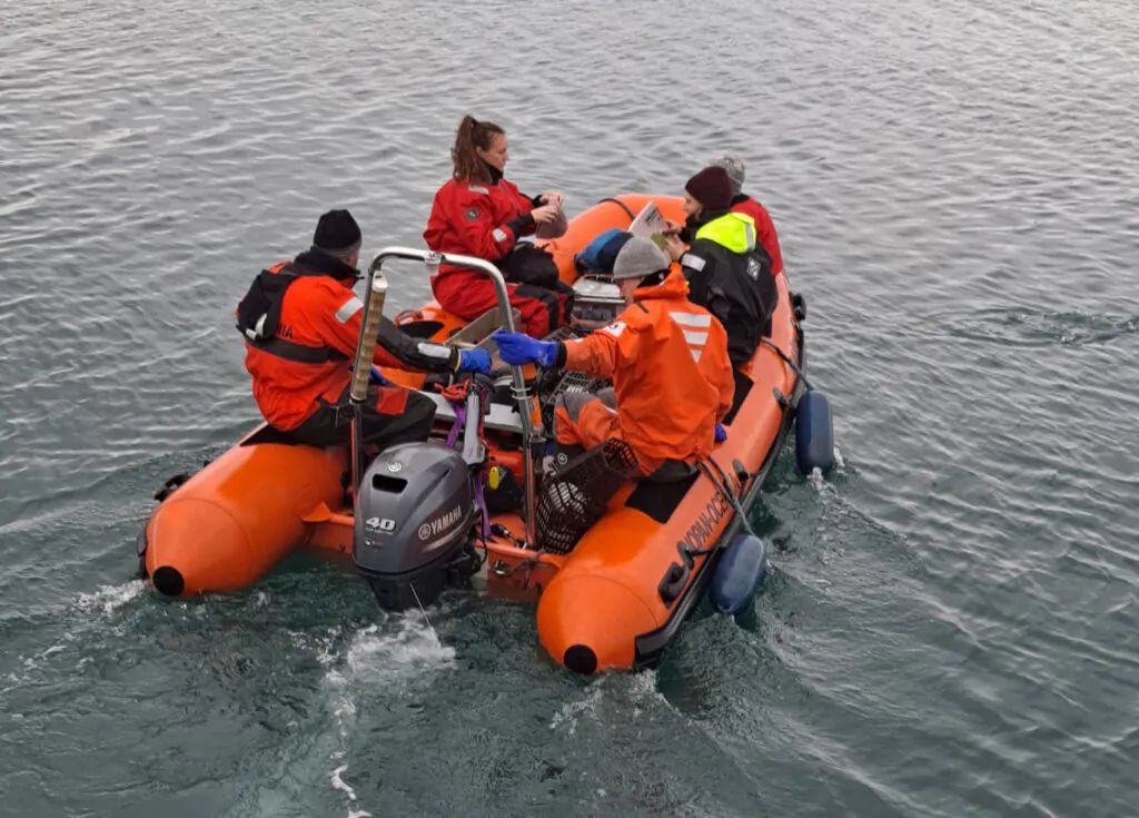 Zdjęcie: grupa ciepło ubranych naukowców w pontonie.