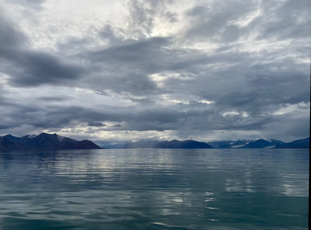 Zdjęcie: krajobraz Arktyki widziany z morza - głównie ocean, niebo i trochę gór.