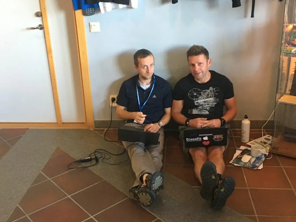 Zdjęcie: dr Artur Palacz, dr Maciej Telszewski siedzą na podłodze z laptopami na kolanach