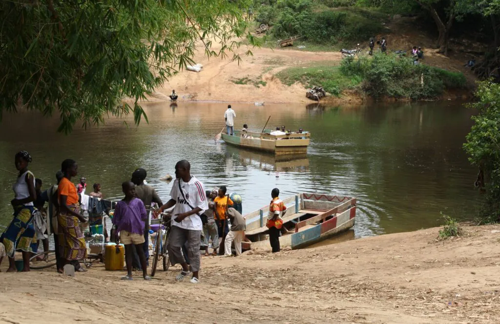 Zdjęcie: grupa migrantów wysiada z łodzi po przeprawie przez rzekę. Liberia.